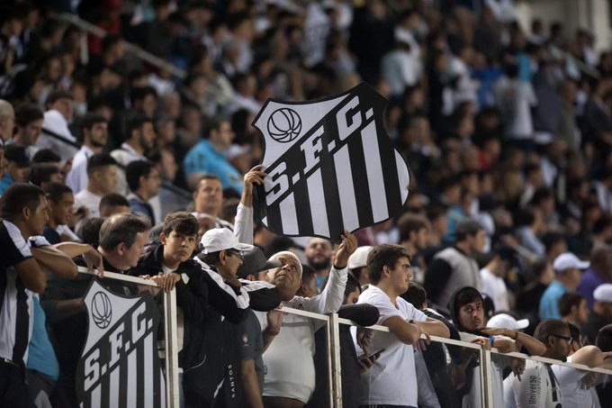 Torcedores do Santos na arquibancada segurando placa que reproduz escudo do clube