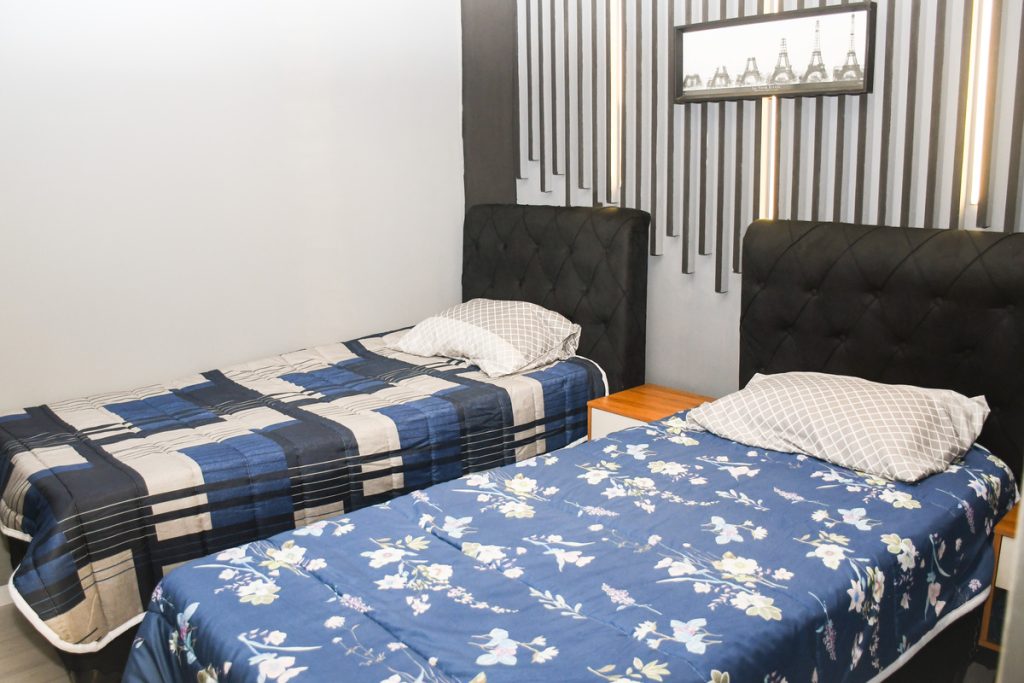 Quarto da república Espaço Novo Começo em São Vicente, com camas organizadas e mobiliário para os moradores.