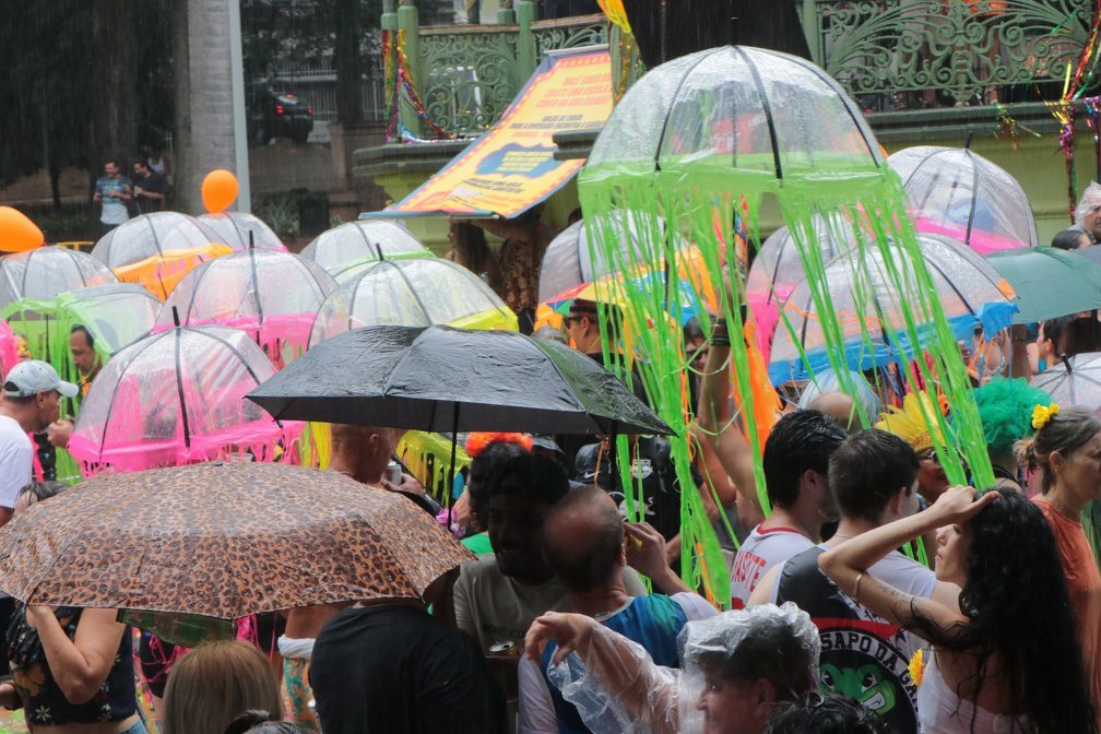 Foliões no Carnaval em Campinas 2026 sob céu nublado com alerta de tempestade e chuva.