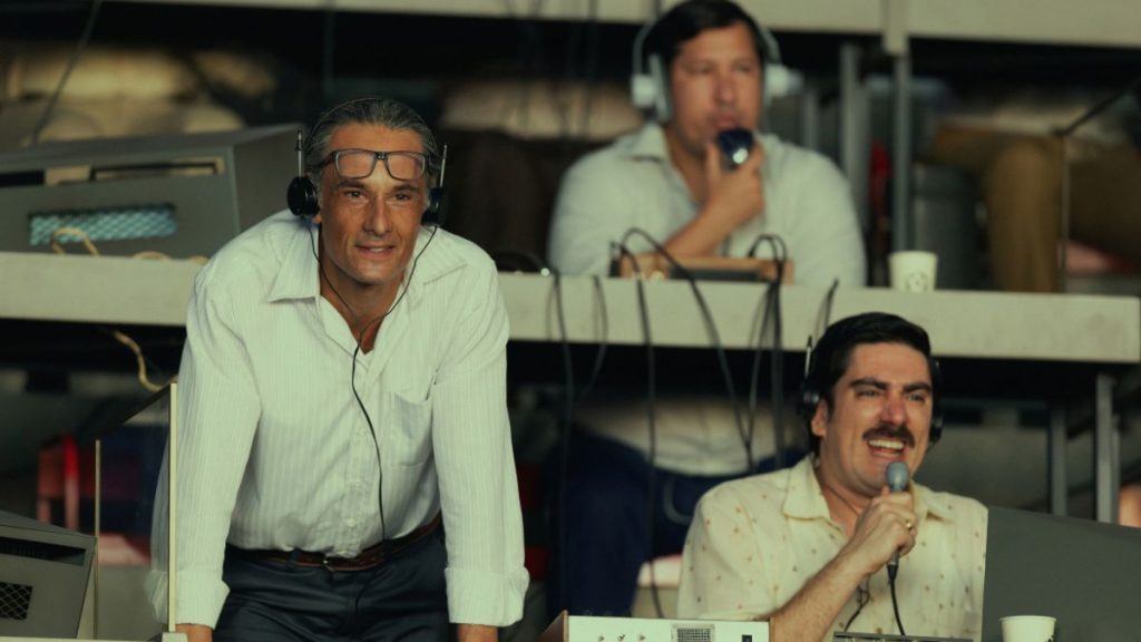 Atores caracterizados como jogadores na série Brasil 70 – A Saga do Tri em campo durante partida de futebol.