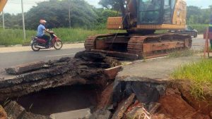 Escavadeira hidráulica atua em obra emergencial para corrigir erosão na avenida John Boyd Dunlop, em Campinas; trecho da pista apresenta cratera e uma faixa está interditada.
