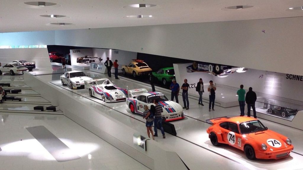 Modelos Porsche clássicos e esportivos em exibição no museu da marca, destacando a paixão por carros de luxo e velocidade.