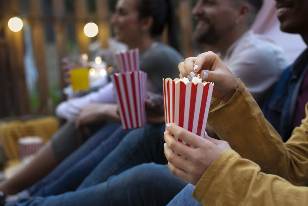 Grupo de amigos em cinema ao ar livre aproveitando a Semana do Cinema com valores especiais.
