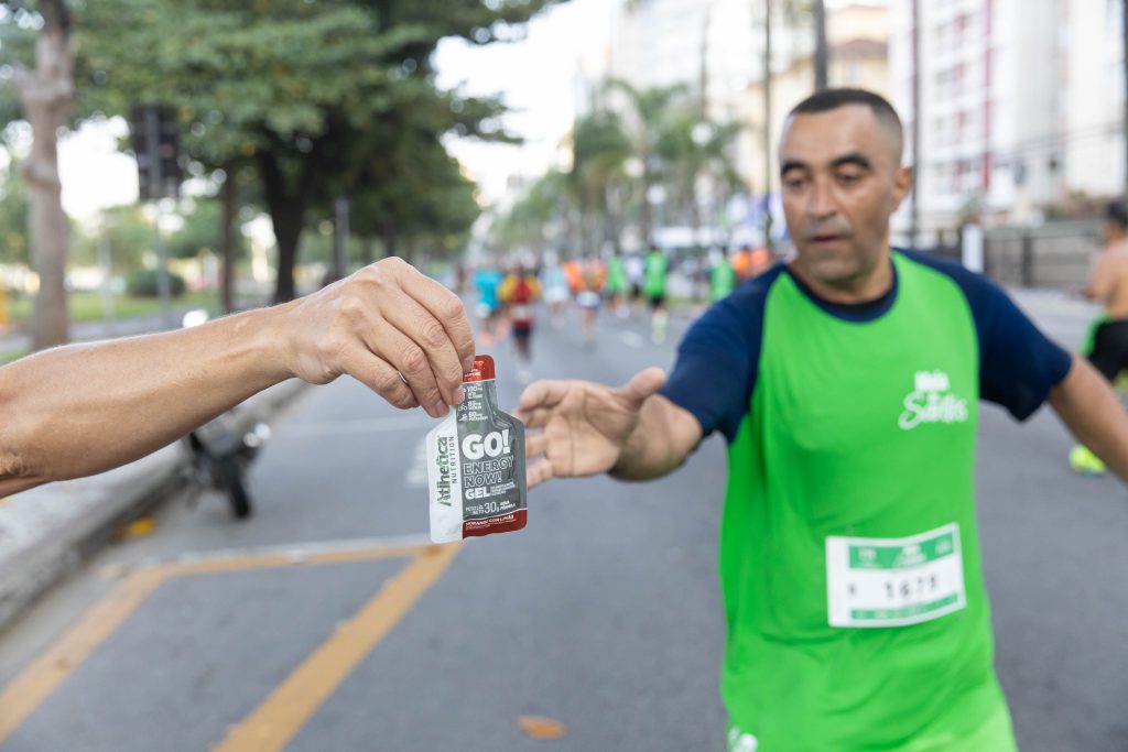 Ponto de apoio com isotônico e frutas para corredores no trajeto da Meia de Santos 2026.