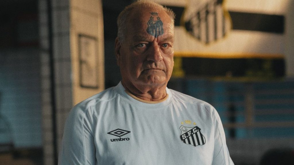 Torcedor símbolo Alemão vestindo a nova camisa branca do Santos FC 2026 em ensaio oficial.