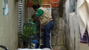 Agente de saúde em Hortolândia inspecionando focos de água parada para combater o mosquito Aedes aegypti.