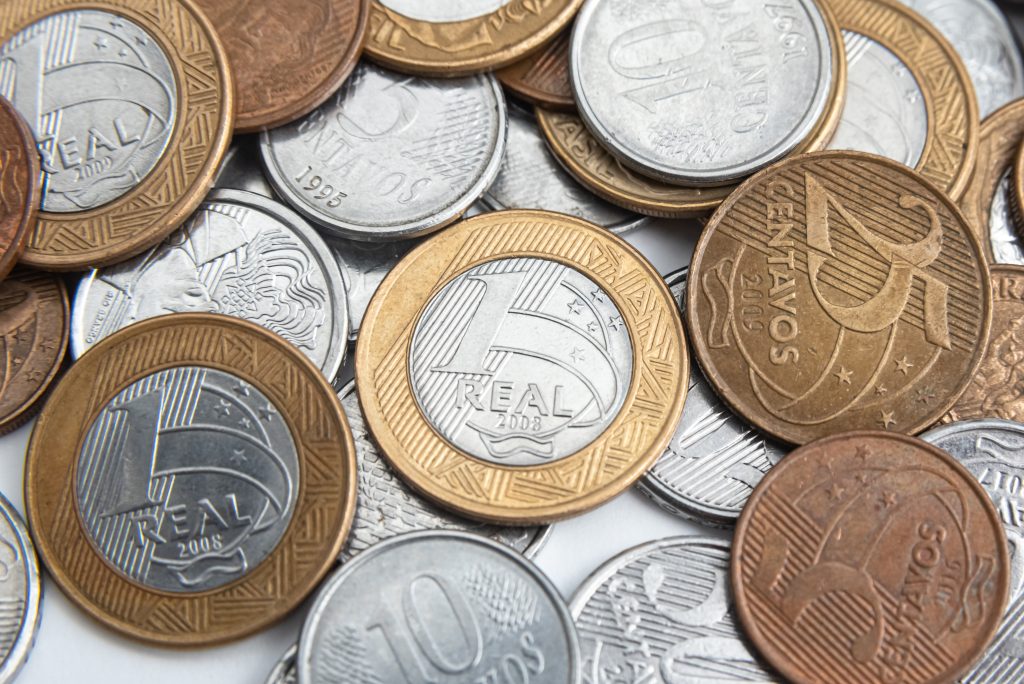 Moedas de Real brasileiro empilhadas representando a projeção de alta na inflação para 2026.