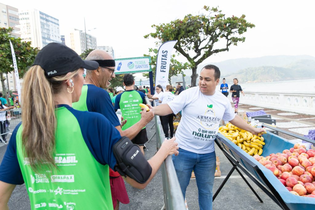 Distribuição de frutas para corredores na Meia de Santos auxiliando na hidratação e recuperação pós-prova.