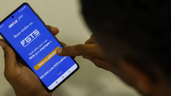 Trabalhador consultando saldo do FGTS no celular para renegociação de dívidas no programa Desenrola 2.0.