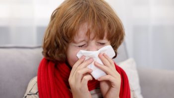 Criança agasalhada no outono prevenindo crises alérgicas e fortalecendo o sistema imunológico infantil.