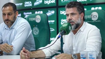 Escudo do Guarani Futebol Clube em estádio, contextualizando a crise financeira e o atraso no pagamento de salários.