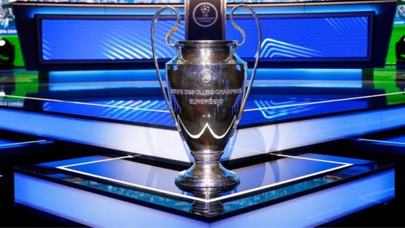 Troféu da Champions League cercado pelos escudos dos oito clubes classificados para as quartas de final.