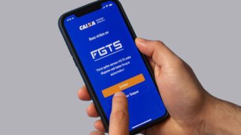 Trabalhador consultando saldo do FGTS no celular para saque de recursos liberados pelo governo federal.