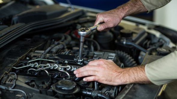 Mecânico realizando manutenção preventiva de carros e inspeção de motor para identificar barulhos.