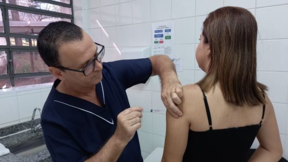 Profissional de saúde aplicando vacina da gripe em Valinhos para imunização de grupos prioritários.