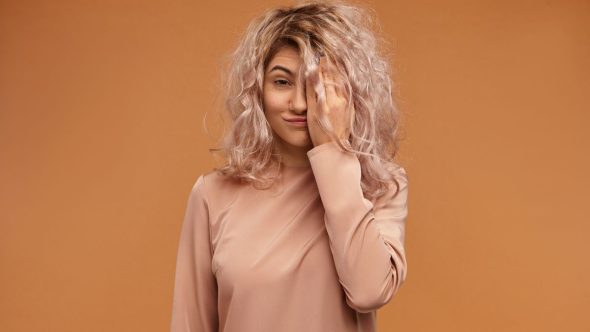 Mulher com cabelos sedosos em cenário de outono destacando cuidados capilares contra ressecamento e queda sazonal.