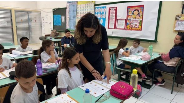 Professor explicando para aluno em escola de Santos
